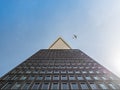 Low angle shot of modern high-rise building with an airplane soaring in the background