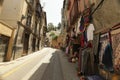 Low angle shot of a narrow street with clothing being sold on the sidewalk in Granada, Spain Royalty Free Stock Photo