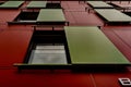 Low angle shot od a red wall of a modern building with green windows Royalty Free Stock Photo