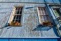 Low angle shot of an old weathered house with flowers on windowsills