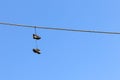 Low angle shot of a pair of shoes hanging from a cable with the breathtaking blue sky in background Royalty Free Stock Photo