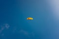 Low angle shot of a person paragliding on a blue sky background