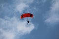 Low angle shot of a person paragliding under the sunlight and a blue cloudy sky