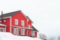 A low angle shot of a red wooden house with several white windows with a dark roof. Clear white sky is on top of the frame. White Royalty Free Stock Photo