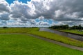 Low angle shot of a river and a path in grassland on a sunny and cloudy day Royalty Free Stock Photo