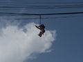 Low angle shot the sneakers hanging from electrical wire against a blue sky with clouds Royalty Free Stock Photo