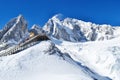 Low angle shot of snowy sharp mountains with a walking trail under a blue sky Royalty Free Stock Photo