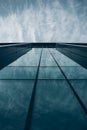 Low angle shot of a tall building in a glass facade under a cloudy sky Royalty Free Stock Photo