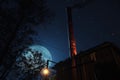 low-angle shot of a tall factory chimney with smoke against a starlit night sky