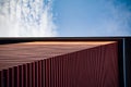 Low angle shot of a tall modern building in a red facade under a cloudy sky Royalty Free Stock Photo