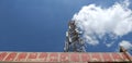 Low angle shot of a telephone tower with clouds in the blue sky looking like smoke coming out of a chimney. Royalty Free Stock Photo