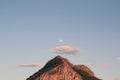 Low angle shot of a top of a mountain under the sky and a small image of the moon in the center Royalty Free Stock Photo