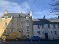 Low angle shot of two brown and white concrete buildings with two cars in front Royalty Free Stock Photo