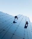 Low angle shot of two persons rappelling at the side of a tall building Royalty Free Stock Photo