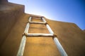 Low angle shot of a wooden ladder leaning against the wall with a clear blue sky in the background Royalty Free Stock Photo