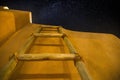 Low angle shot of a wooden ladder near the building under the dark sky full of stars Royalty Free Stock Photo
