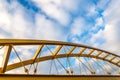 Low angle shot of a yellow cable-stayed bridge with a blue cloudy sky in the background Royalty Free Stock Photo