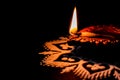 Low angle side profile view of beautiful terracotta lamp on rangoli  art against black background. diwali concept Royalty Free Stock Photo