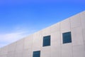 Low angle and side view of glass windows on modern white concrete building wall against blue sky Royalty Free Stock Photo