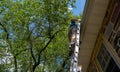 Low angle side view of man on ladder cleaning gutters of stone home Royalty Free Stock Photo