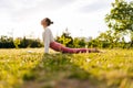 Low-angle side view of sportive and healthy young woman in white sportswear practicing yoga in green park doing Upward Royalty Free Stock Photo