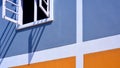 White wooden window on blue and orange painted cement wall decoration Royalty Free Stock Photo