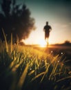 low angle , silhouette of a guy jogging in the morning on an empty road, diminishing perspective, dew on the grass, sunlight Royalty Free Stock Photo