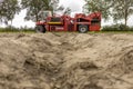 Farmland soil with potato harvester in the background