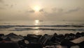 Low-angle of a sunset over sea stones on the beach shining sun and cloudy sky background Royalty Free Stock Photo