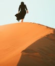 Low angle tracking view beautiful woman in long dress feet follow walk on KAshan desert dunes Royalty Free Stock Photo