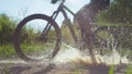 LOW ANGLE: Unrecognizable active person rides their bike into a muddy puddle.