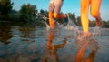 LOW ANGLE: Unrecognizable couple jogging in the shallows of a tranquil river.