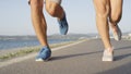 LOW ANGLE: Unrecognizable couple jogs down peaceful walkway near the ocean.