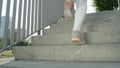 LOW ANGLE: Unrecognizable female jogger runs up a flight of concrete stairs.