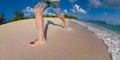 LOW ANGLE: Unrecognizable male tourist runs barefoot along the tropical beach.