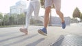 LOW ANGLE: Unrecognizable sporty couple running on a sunny morning in the city