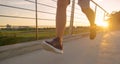LOW ANGLE: Unrecognizable young man jogs across asphalt bridge at golden sunset.