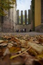 Low-angle vertical shot of the autumn leaves with a family standing in front of the ancient fortress