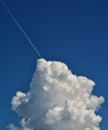 Low-angle vertical shot of the plane contrail in the blue clouded sky