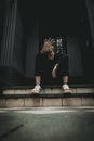 A vertical shot of a young hipster female raised her hand for dissuade while sitting on stairs