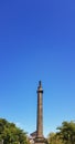 Low-angle vertical view of the ancient Melville Monument in the presence of lush trees and clear sky