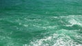 Low angle video - moving over the rocks towards the sea, view to green water crashing on rocks at the end making white spray