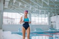 Low angle view of active senior woman preapring for swim in indoors swimming pool. Royalty Free Stock Photo