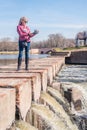 Low angle view of an adult woman standing on a brick walkway in the park holding a gimbal with phone