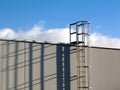 Aluminum roof access ladder detail with safety cage. long abstract shadow.