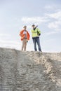 Low angle view of architect showing something to colleague at construction site against sky Royalty Free Stock Photo