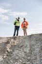 Low angle view of architect showing something to colleague at construction site against sky Royalty Free Stock Photo