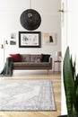 Low angle view of an artistic living room interior with a large, black, spherical pendant light above a brown sofa.