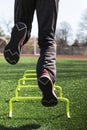 Low angle view of athlete jumping on one leg over mini hurdles from behind Royalty Free Stock Photo