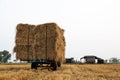 Low-angle view of a walk-behind tractor carrying piles of straw bales Royalty Free Stock Photo